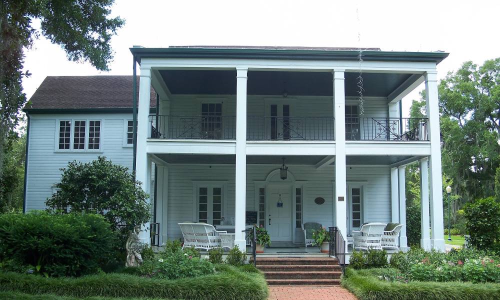 The white clapboard Leu House with its two-story porch at Harry P. Leu Gardens in Orlando