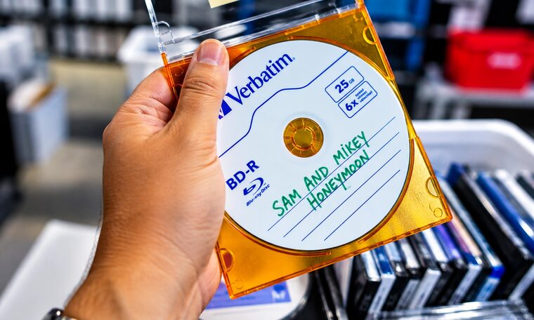 A Forever Studios technician holding a finished Blu-ray labelled with a customer order