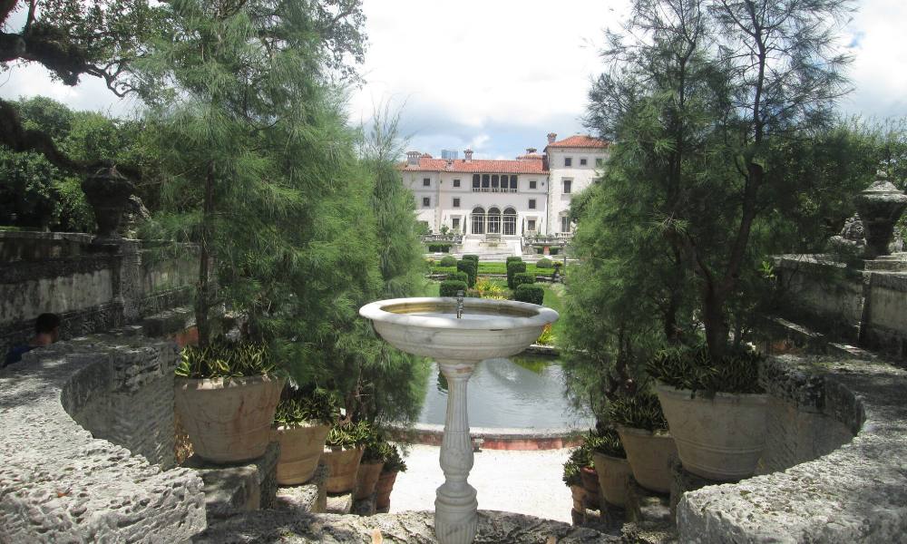 The main house at Vizcaya seen across the formal gardens, with a stone fountain in the foreground