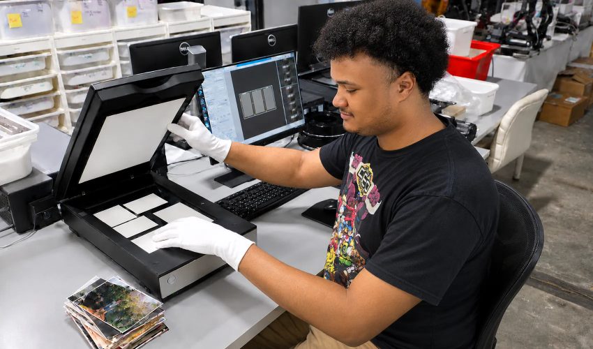 Production technician scanning documents with flatbed scanner at digitization facility workstation