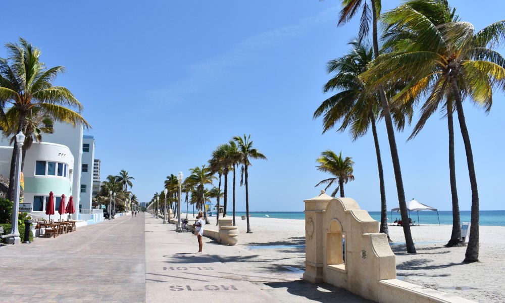 The paved Broadwalk promenade along Hollywood Beach with palms and low buildings
