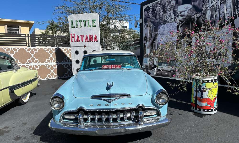 A vintage 1950s car parked beneath a Little Havana sign on Calle Ocho in Miami