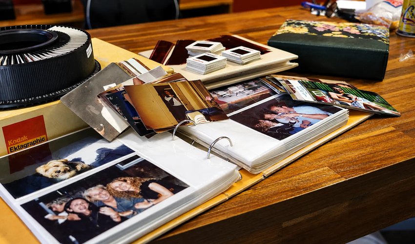 Technician hand-scanning vintage family photograph at 600 DPI preservation studio workstation
