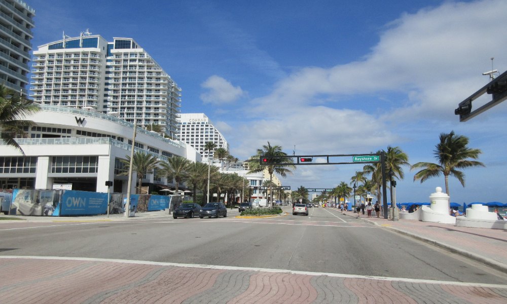 The A1A beachfront and wave wall at Fort Lauderdale Beach with palms and high rise buildings