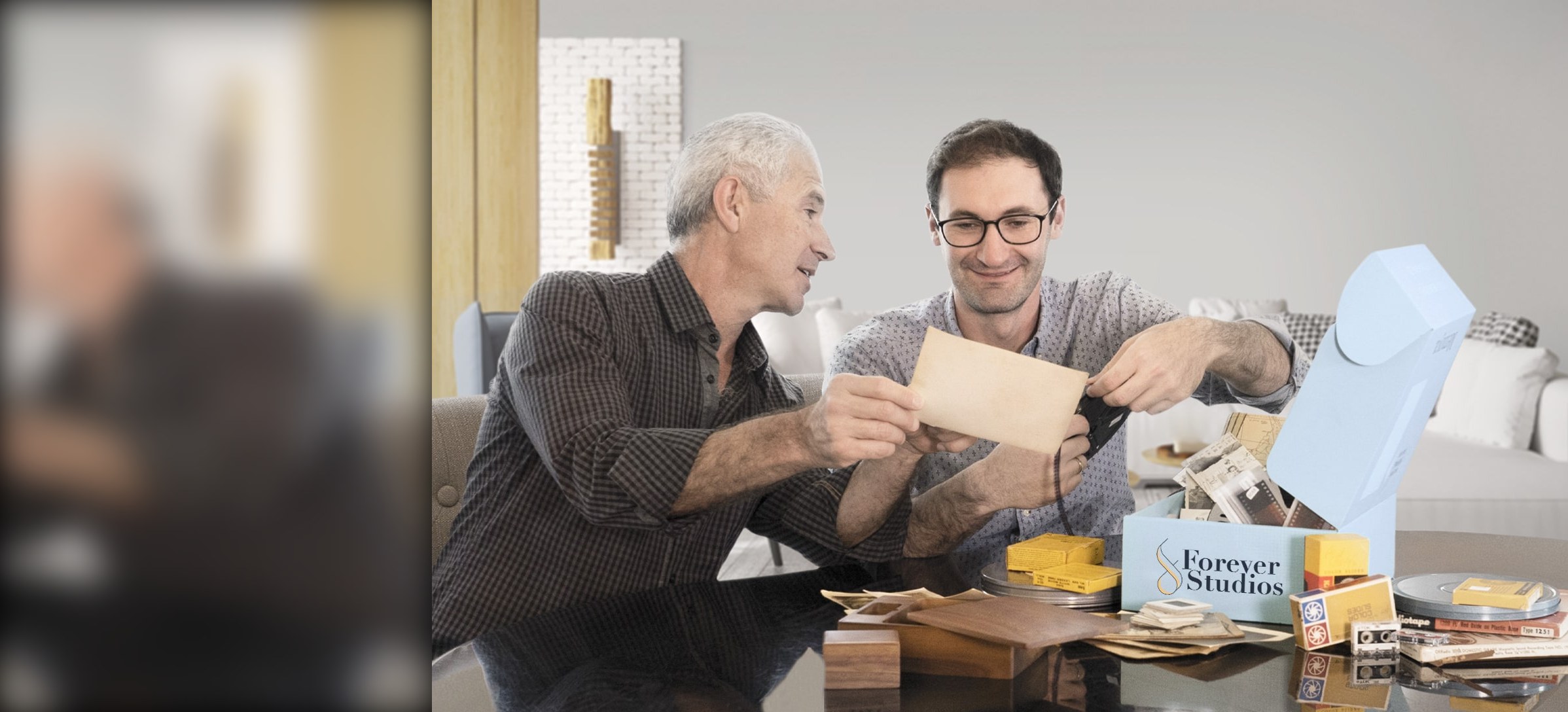 A father and son opening a Forever Studios box of film reels, photo envelopes and slides at their table