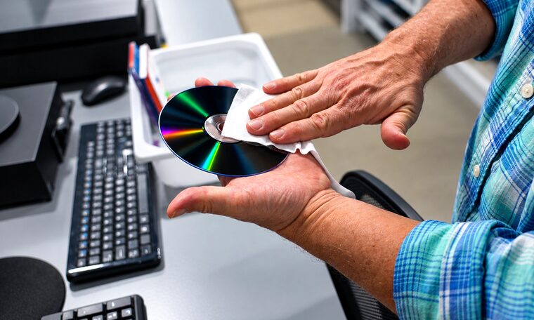 A Forever Studios technician cleaning a DVD by hand before transfer